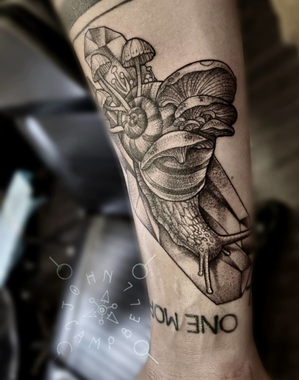 Black and grey tattoo of snail with mushrooms growing from its shell by John Campbell at Sacred Mandala Studio tattoo parlor in Durham, NC.